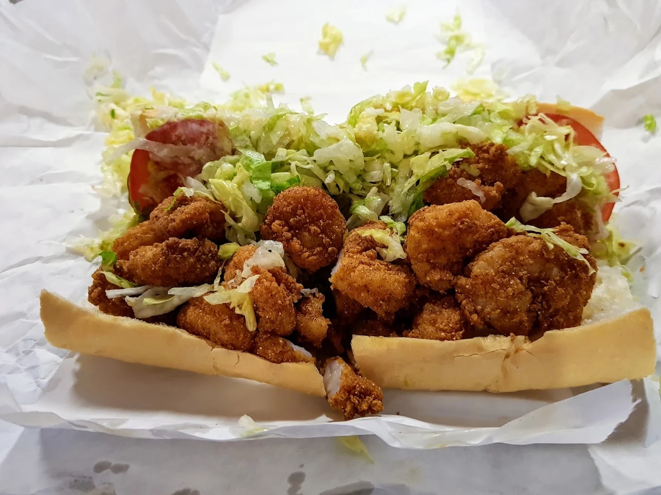 Fried shrimp on a French loaf with lettuce, on white butcher paper.